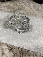 Front right angle view of clear faceted Swarovski crystal elephant figurine showing detailed ears, trunk, and black eyes.