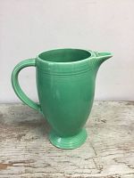 Full side view of green ceramic vintage Fiesta pitcher showing handle and spout