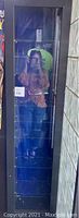 Front view of the tall black wood display case with glass door closed, reflecting person taking photo, showing 7 glass shelves inside.
