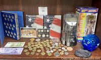 Overall lot showing coin collection books, coin proofs, assorted coins and paper money, two coin banks and a wooden nickel.