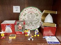 Photo of entire lot showing Lladró Angel Bell ornament in box, Coca-Cola Santa ornament in plastic case and box, Coca-Cola yellow crate magnet, multiple McDonald's Christmas character figurines, and decorative Christmas wall plate with recipe text and heart design.