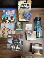 Overview photo of the Star Wars collectibles including action figure card, books, booklet, and water bottle on a table