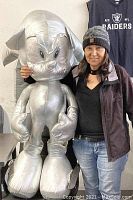 Photo showing the giant silver Sonic the Hedgehog plush standing next to a person for size reference.