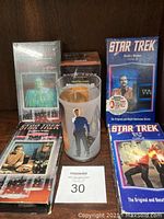 Group photo of all items showing four Star Trek VHS tapes and one Spock tall drinking glass