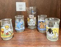 Set of 7 collectible glasses including E.T. tall glass and 6 Welch's promotional glasses featuring classic cartoon characters