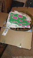Folded colorful baby crib pads and sheets in a cardboard box