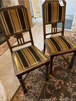Pair of wooden dining chairs with striped fabric upholstery, decorative nailhead trim, and turned barley-twist legs.