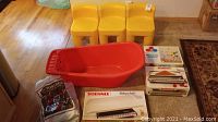 Red toddler bathtub, Soehnle kitchen scale packaging, Disney mobile and other boxed items arranged on floor