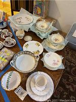 Overview photo of mixed china pieces including Nikko tea cup and saucer sets, Royal Standard saucers, Smith dessert bowls, soup bowls, floral plates, and Kaiser bowl with handles.