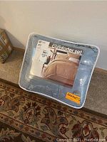 Photo of packaged comforter set in clear plastic carrying case with picture of bedding on label and brand KC Stanley indication.