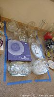 Assorted clear glass dishes and glassware, including boxed WMF Tortenplatte plate and various bowls and serving dishes.