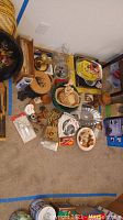 Overview of the lot showing various kitchen tools, decorative items, baskets, and utensils arranged on carpet
