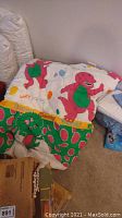 Barney comforter with large image of Barney character on white and green background.