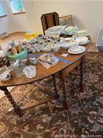 Oak gate-leg table with various items on top, showing overall tabletop surface and leg design.