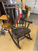 Overall view of black wooden rocking chair showing design and condition around room.