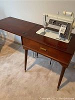 Full view of Singer Touch & Sew Model 600 sewing machine mounted in wooden sewing table with fold-out extension and drawer.