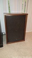 Front view of speaker showing walnut veneer cabinet and lattice grill