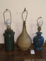 Three ceramic lamps shown side by side: green vintage milk pail style, tall sand ribbed pottery, and blue glazed vase shape.