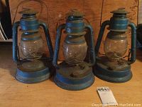 Front view of all three blue Dietz Little Wizard No. 1 lanterns showing condition, size, and grouping.