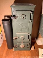 Front view of the green cast iron Jotul No507 coal burning stove with horse relief and pipe sections