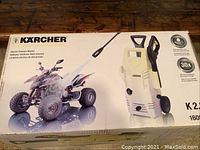 Boxed Karcher electric pressure washer showing the unit and usage example with all-terrain vehicle.