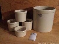 Full set of five white ceramic kitchen crocks including one large 1-gallon crock marked No. 1 with blue crown logo and four smaller crocks of various sizes.
