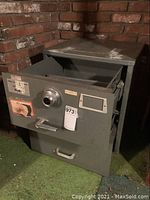 Front view of Mosler security safe showing one drawer open with combination lock and handle, label visible on front.