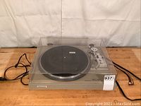 Front-left angle view showing dust cover, platter, tonearm and RCA cables