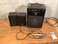 Full view of MPS-20 amplifier, two Realistic Minimus-7 speakers, and Panasonic wired microphone on wooden surface with visible cables.