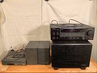 Full view of the stereo equipment set including receiver, subwoofer, speakers and compact receiver with wires.
