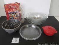 Full lot display showing Brie baker, glass bowls, pie plates, cake pan, cookbook and milk bottle.