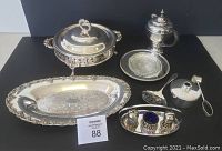 Full lot view showing all items on table: covered casserole dish with lid, bun tray, small hot water pitcher, butter dish with glass insert, Sterno set, and silverplate and cobalt blue glass salt and pepper set on tray with spoon.