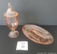 Two pink Depression glass items displayed: an upright candy dish with lid and a divided appetizer dish, both etched with floral details, on a dark surface with a numbered MaxSold tag.