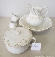 Set of 6 pieces including wash basin, large water pitcher, chamber pot with lid, small water pitcher, and flower vase with white porcelain and gold trim detailing.