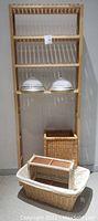 Wooden over-the-toilet shelf unit with multiple shelves, holding two frosted glass ceiling light fixtures and two wicker baskets at base.