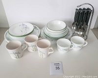 Lot contents of Corelle and Harmonic dishes with cutlery set displayed on table