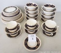 Full set display showing arrangement of plates, teacups with saucers, soup bowls with under plates in cobalt blue and gold pattern.