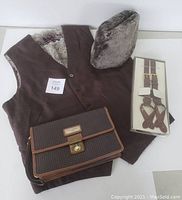All items arranged together: vest, boxed brown leather suspenders, lambskin fur hat, and Ted Lapidus carry-all bag.