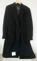 Full front view of black overcoat on hanger against white background