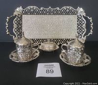 Front view of entire Turkish coffee set including tray, two cups in holders with saucers, and covered sugar dish, all in silver-tone metal with ornate patterns.