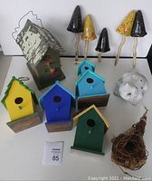 Overview photo of all items showing five ceramic mushrooms, multiple painted wooden birdhouses, metal roof birdhouse, twig nest birdhouse, and garden frog
