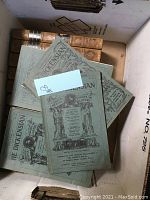 Boxed view of green softcover journals with spines of leather-bound books visible underneath
