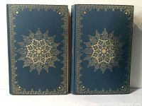 Two volumes with dark blue covers and gilt ornamental design on front covers, dust jackets protecting them