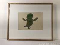 Frontal photo of the framed indigenous painting showing a green bird on beige paper, centered within a wooden frame.