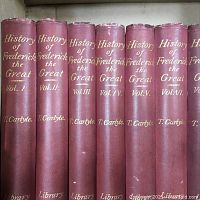 Spines of 7 volumes showing title, author and volume numbers in gold lettering on red cloth binding.