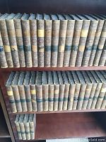 View of two shelves holding volumes of Waverly Novels with leather spines showing decorative embossing and spine labels in various colors. Wear and missing spine labels visible.