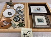 Assorted animal figurines including birds, dogs, bunnies, frogs, fish-themed plates and figurines arranged on wooden trays.