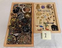Two wooden trays filled with assorted costume jewelry separated by type, photographed to show overall lot contents.