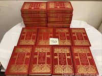 Overview of fourteen red hardcover Memoir Series books with gold embossed decoration stacked and laid out.