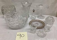 Group photo showing assortment of cut crystal glassware including vases, bowls, small bottle with stopper, small plate with silver rim, and candle holders.